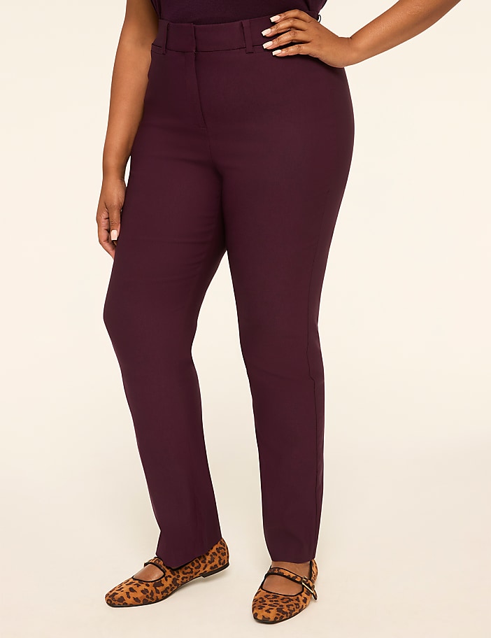 A woman in burgundy pants and leopard print flats stands against a plain, light-colored background.