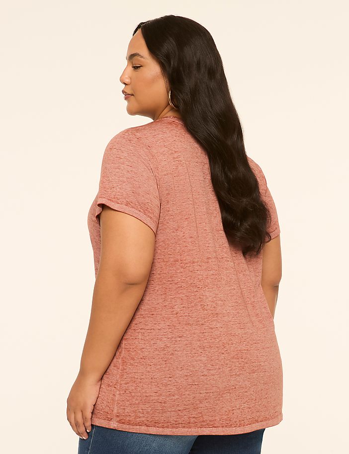 A woman in a pink t-shirt and jeans is shown from the back against a plain, light-colored background.
