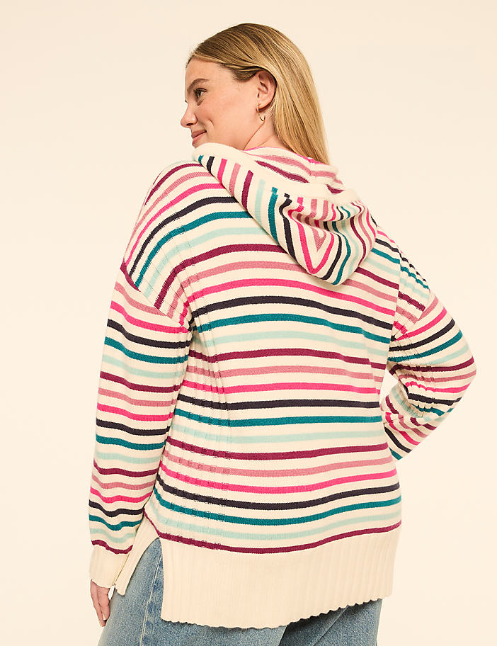 A woman in a striped hoodie stands against a plain, light-colored background.