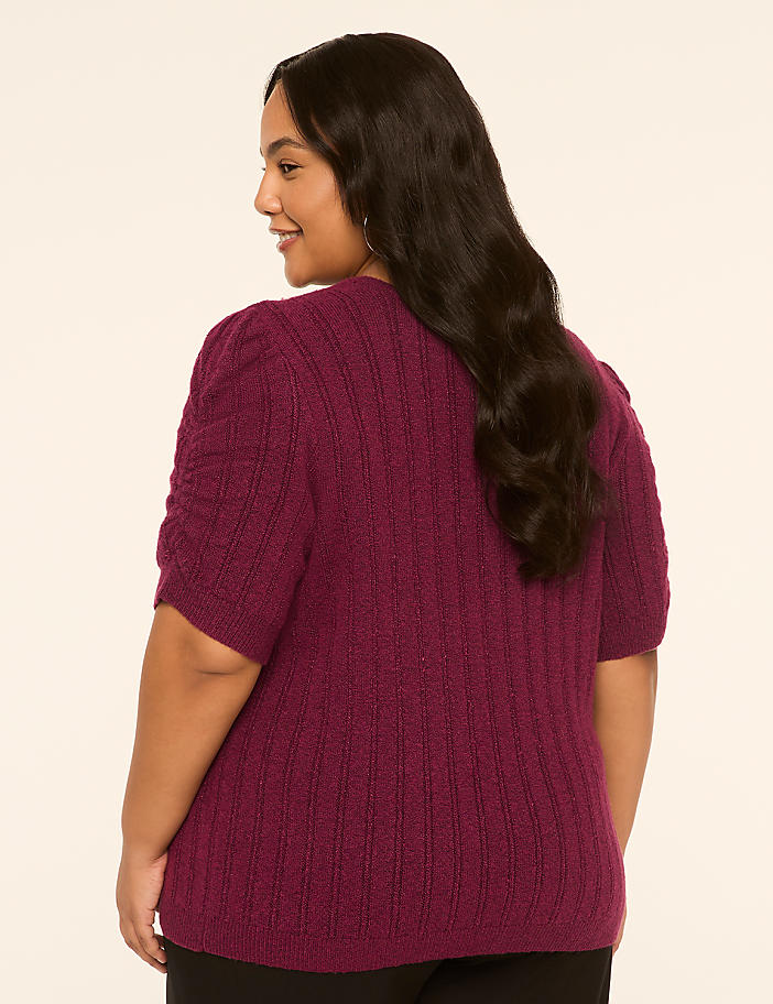 A woman in a purple sweater is shown from the back against a plain, light-colored background.
