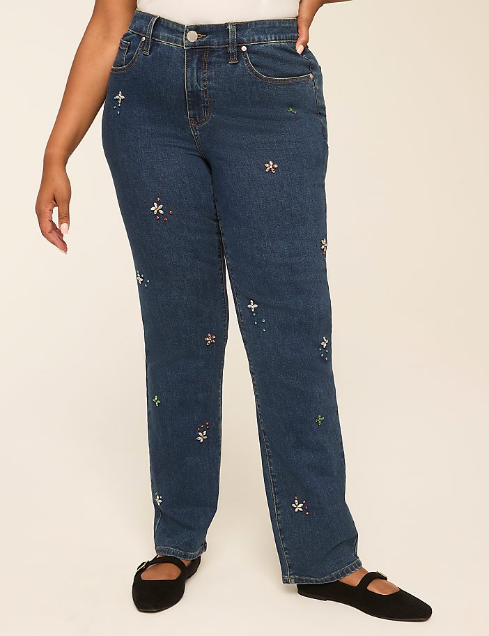 A person wearing embroidered denim jeans stands against a plain, light-colored background.