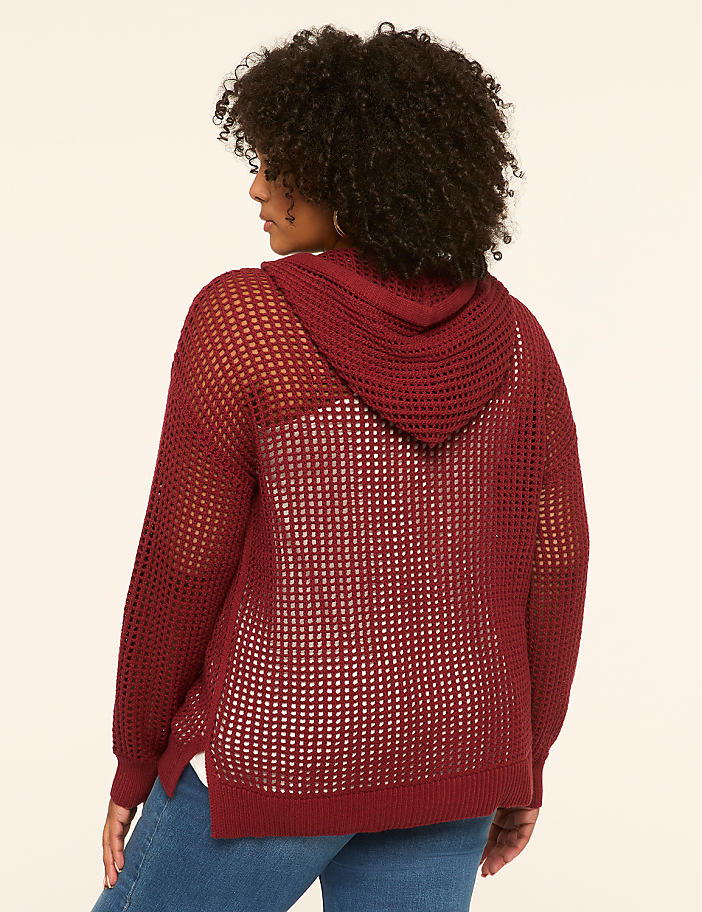 A woman in a maroon hooded sweater stands against a plain, light-colored background.