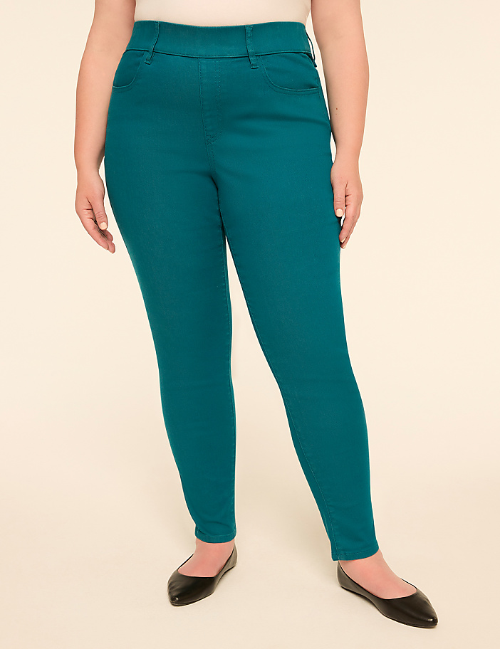 A person in teal pants and black flats stands against a plain, light-colored background.
