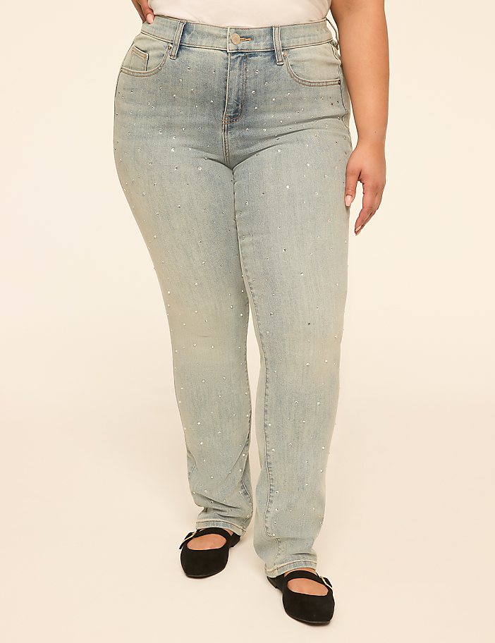 A person stands in light-wash, rhinestone-embellished jeans and black flats against a plain, light-colored background.