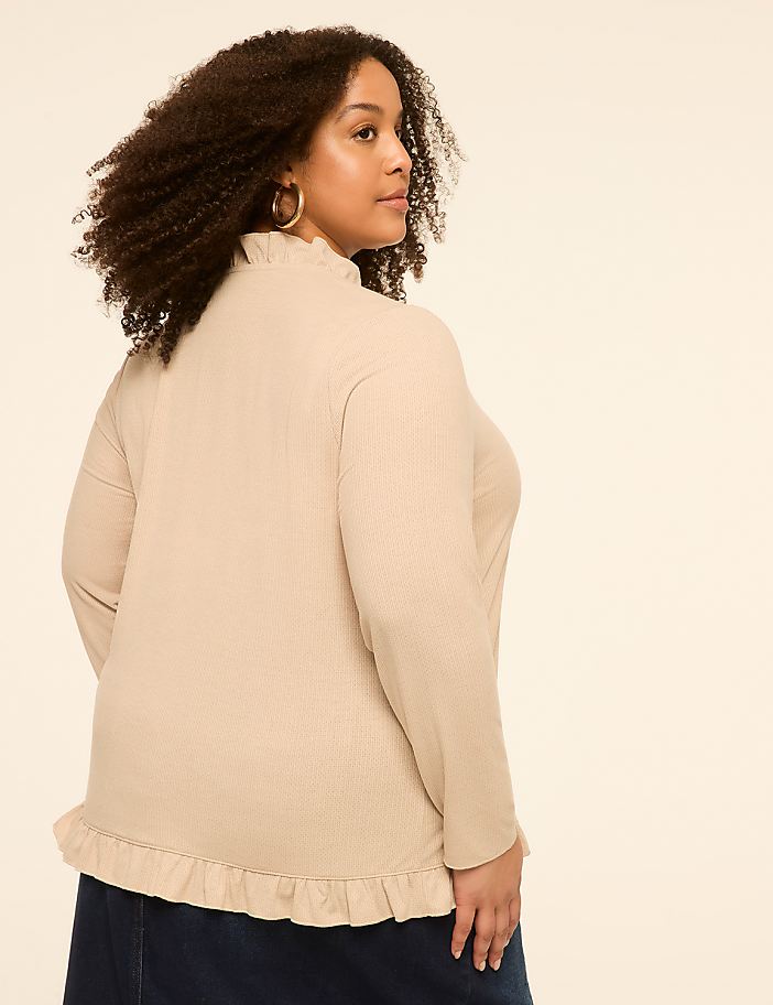 A woman with curly hair, wearing a beige ruffled top and dark skirt, is shown from the back against a plain cream background.