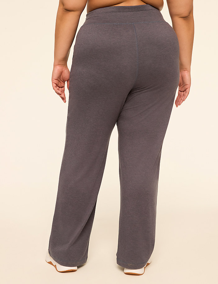 A person wearing dark gray sweatpants stands against a plain, light-colored background.