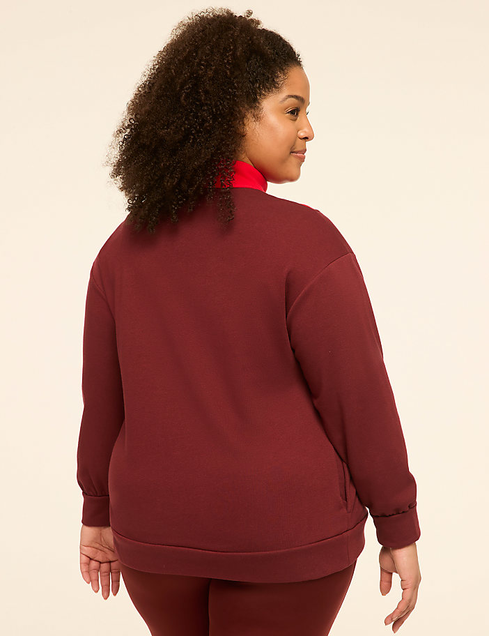 A woman in a maroon sweatshirt and red turtleneck stands against a plain, light-colored background.