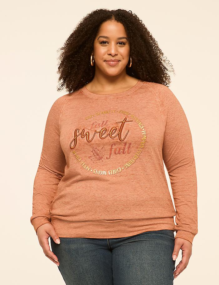 A woman with curly hair smiles at the camera, wearing a rust-colored sweatshirt with a circular graphic that says "fall is sweet fall," against a plain, light-colored background.