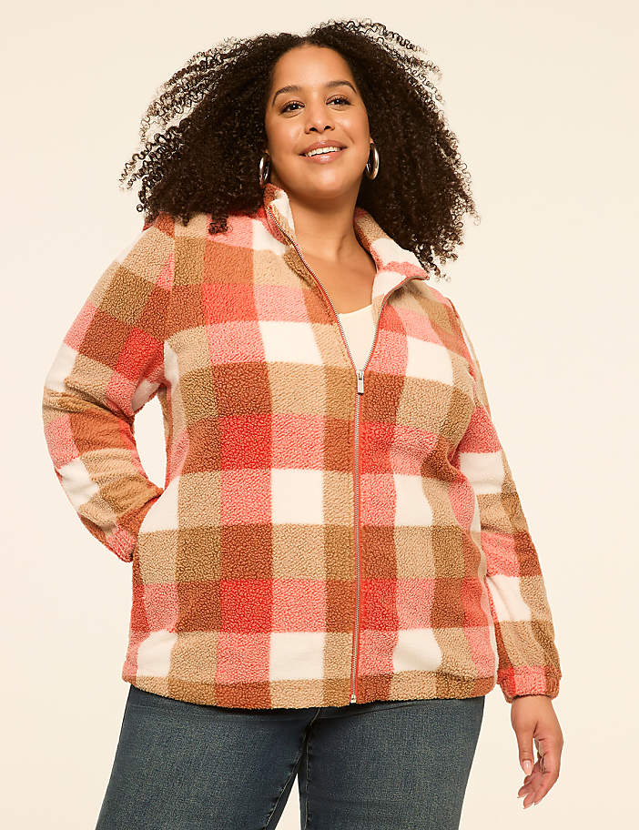 A woman in a plaid fleece jacket stands against a plain, light-colored background.