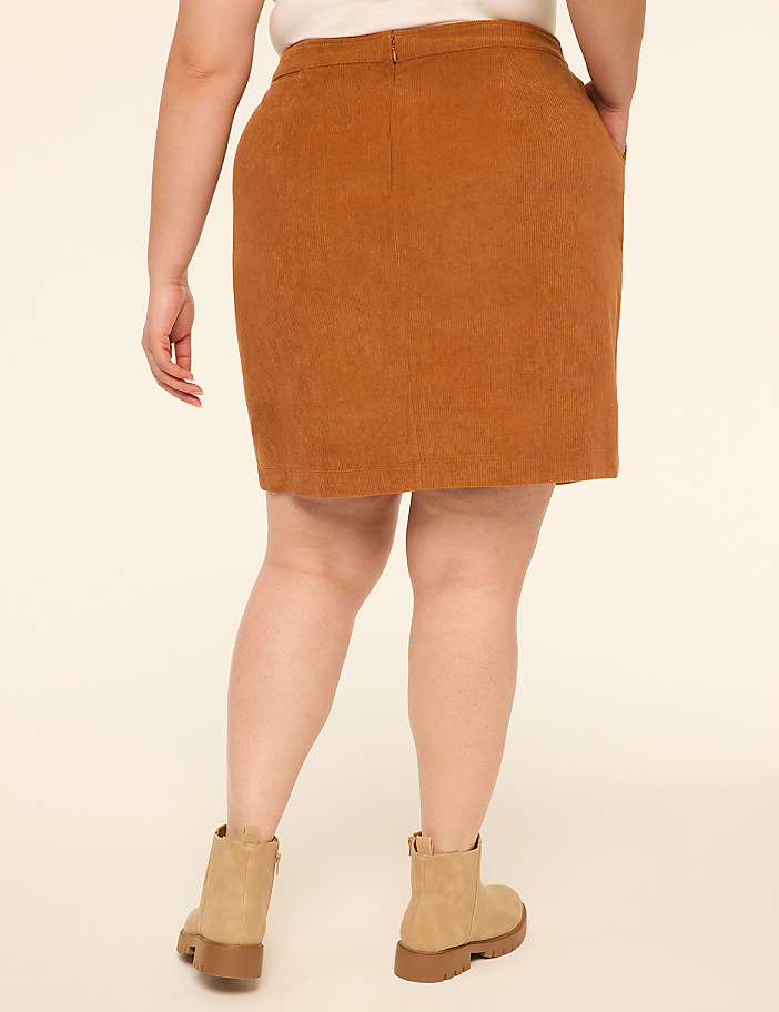 A person wearing a brown corduroy skirt and tan boots stands against a plain cream background.