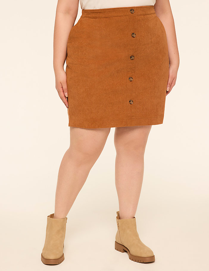 A person wearing a brown corduroy skirt and tan boots stands against a plain, light-colored background.
