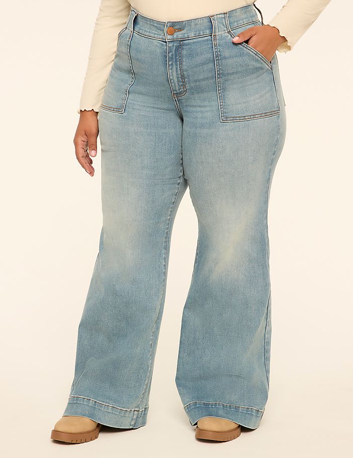 A person wearing light-wash flared jeans with large front pockets stands against a plain, light-colored background.