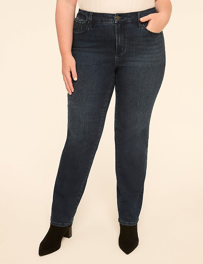 A person wearing dark wash denim jeans and black boots stands against a plain, light-colored background.
