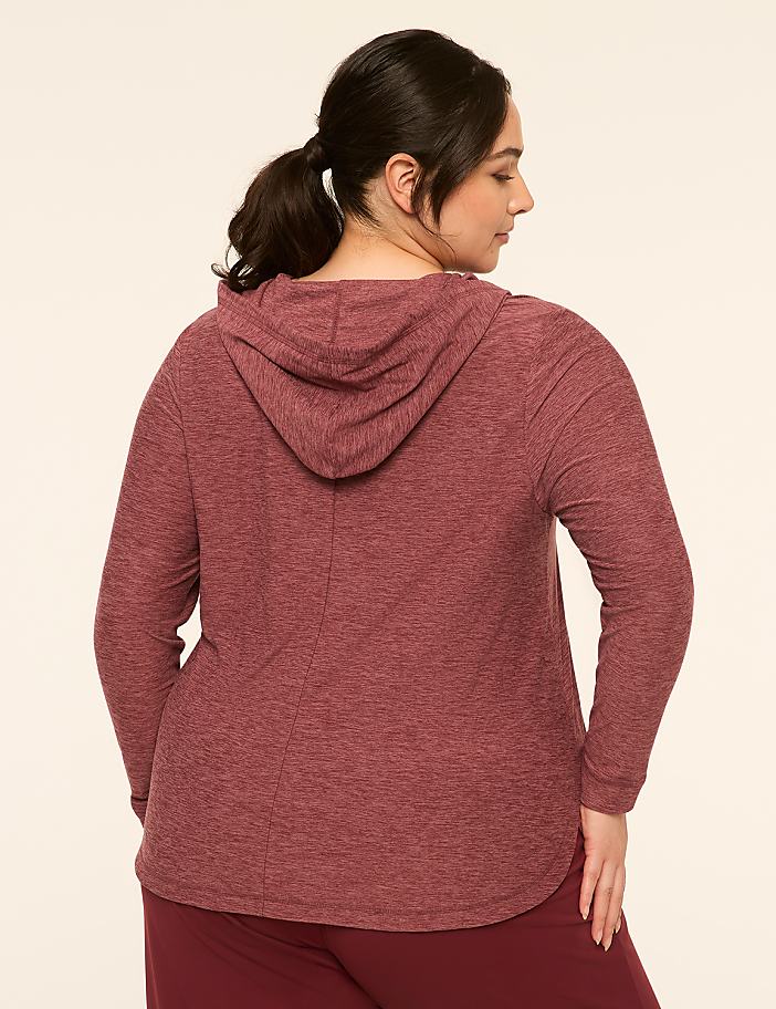 A woman in a maroon hooded sweatshirt and maroon pants stands against a plain, light-colored background.