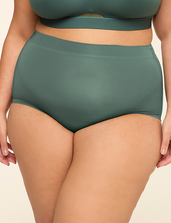 A person wears high-waisted, seamless green underwear and a matching bra against a plain background.