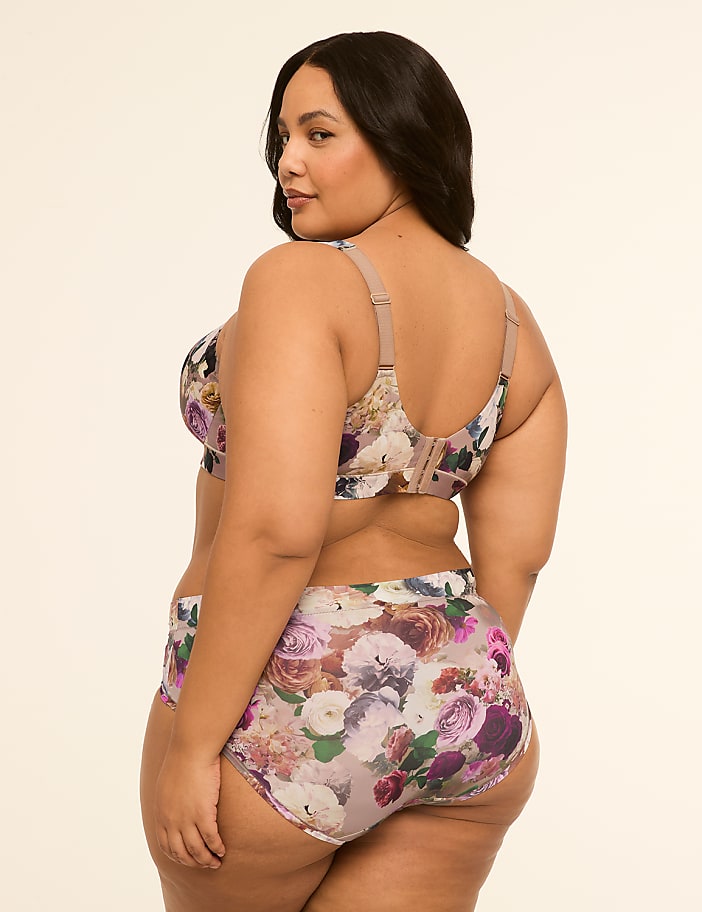 A plus-size woman in a floral bra and underwear is shown from the side against a plain, light background.