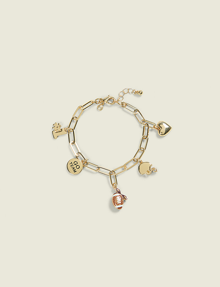 A gold charm bracelet with football, heart, and team-themed charms rests on a pale yellow background.