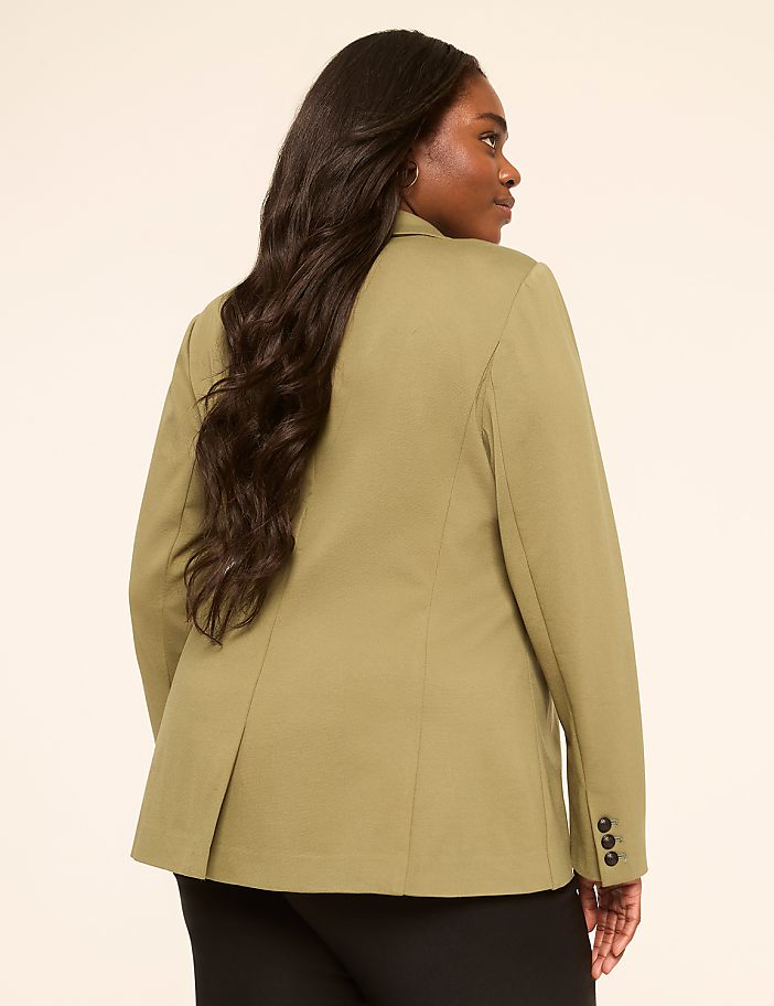 A woman in a green blazer is shown from the back, with a plain, light-colored background.