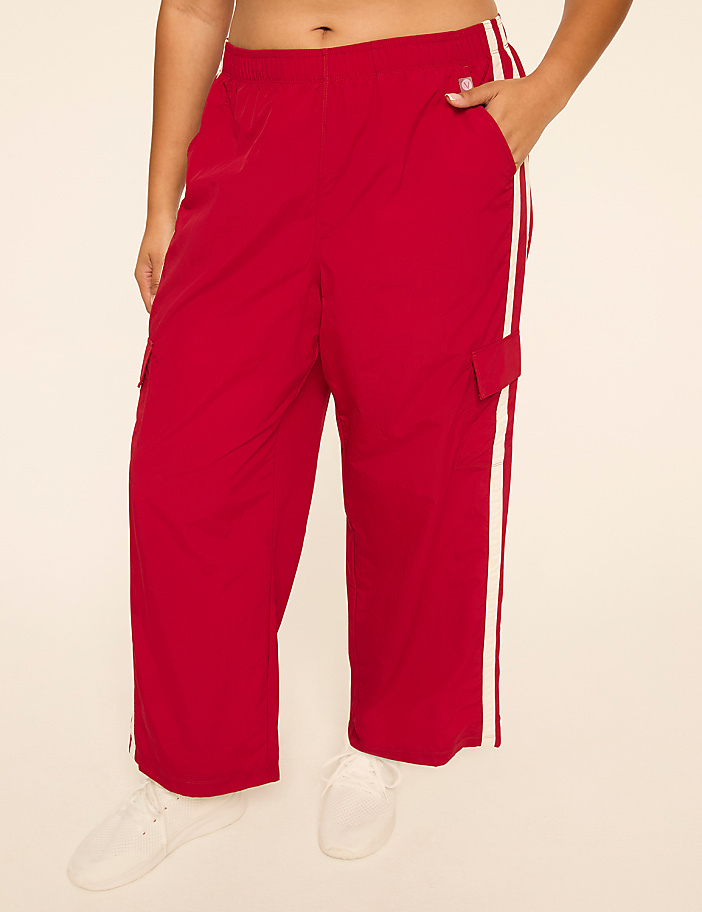 A person stands in red cargo pants with white stripes down the sides, against a plain, light-colored background.