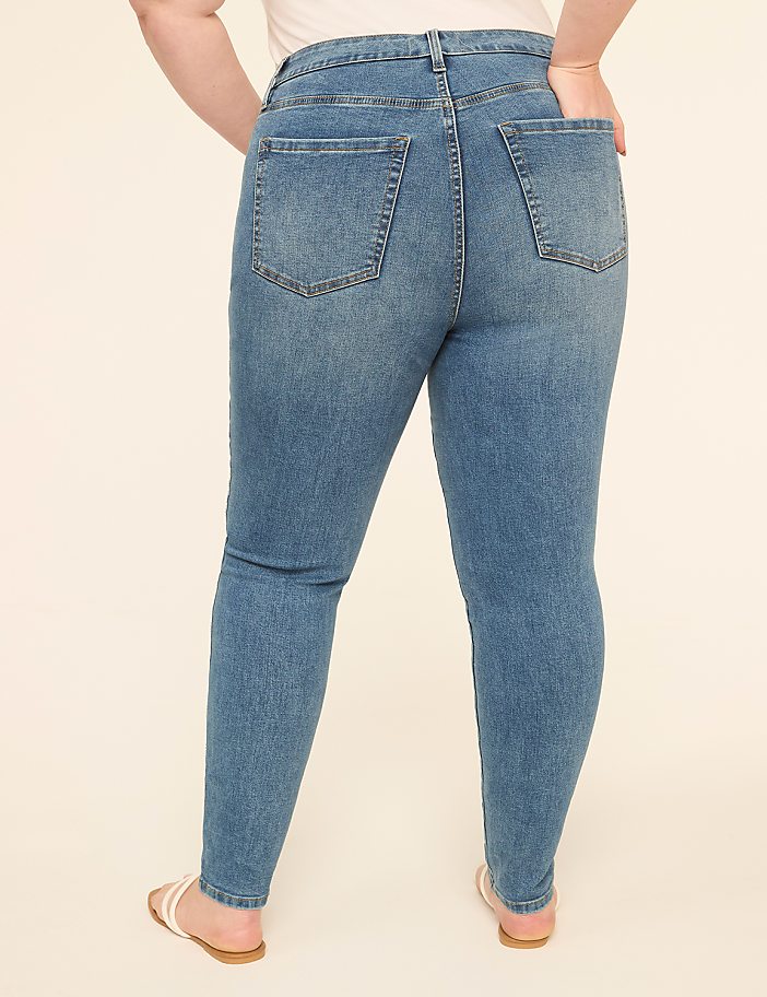 A person wearing blue denim jeans stands with their back to the camera against a plain, light-colored background.