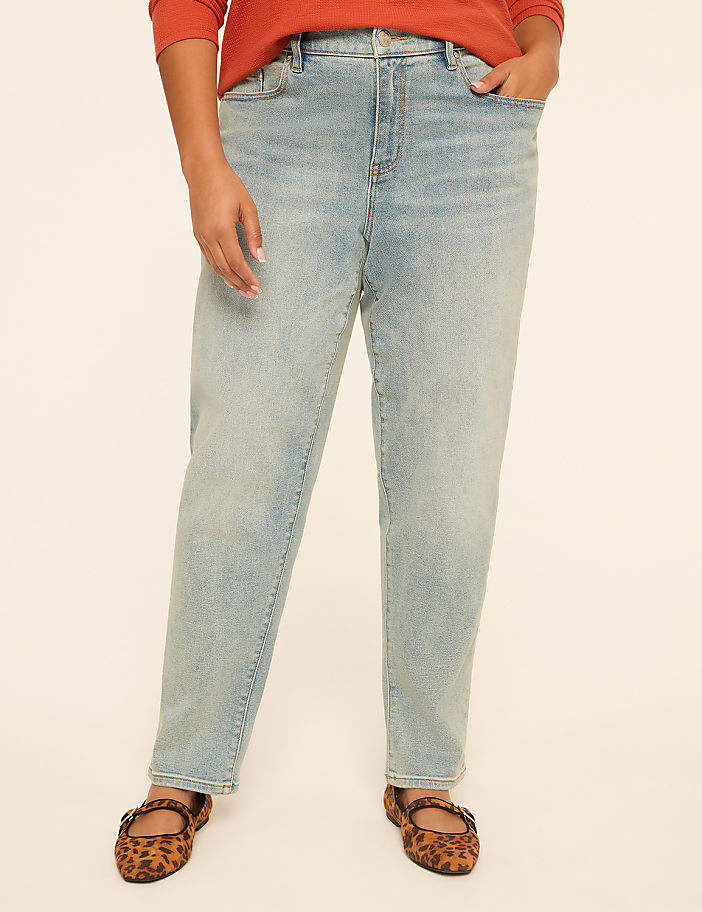 A person wearing light-wash jeans and leopard print flats stands against a plain, light-colored background.