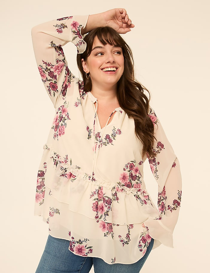 A smiling woman in a floral blouse poses against a plain, light-colored background.