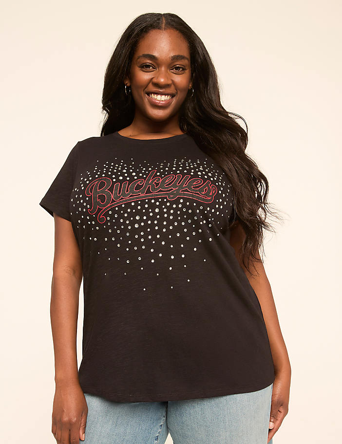 A smiling woman in a black t-shirt with "Buckeyes" written in glitter stands against a plain, light-colored background.