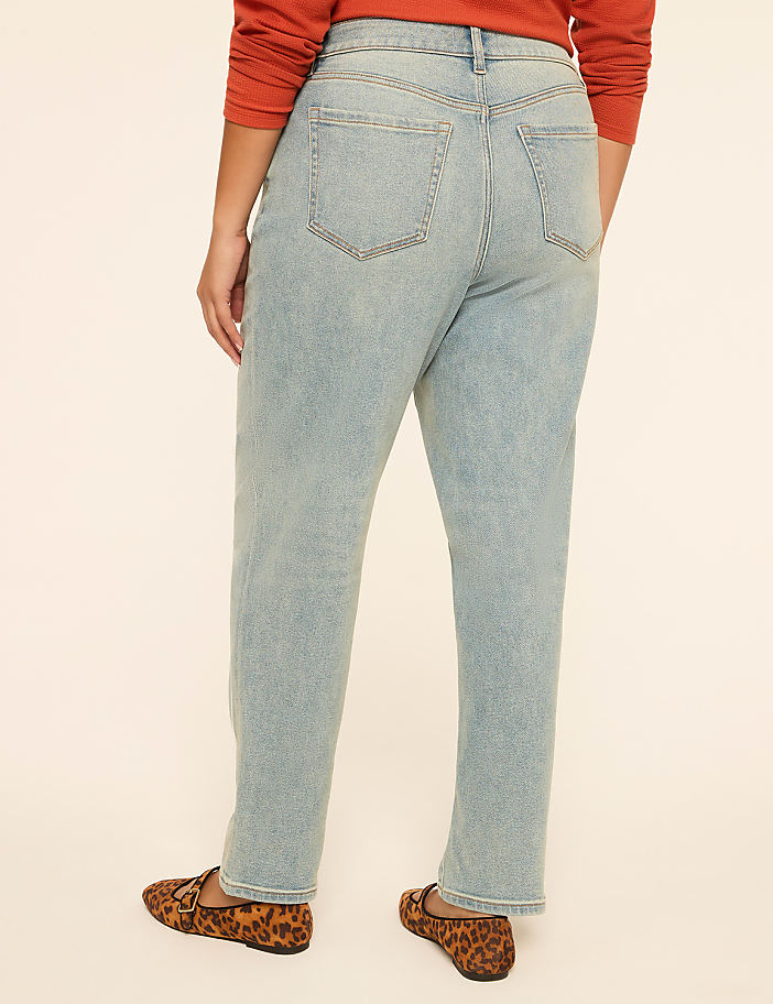 A person wearing light-wash jeans and leopard print loafers stands against a plain, light-colored background.