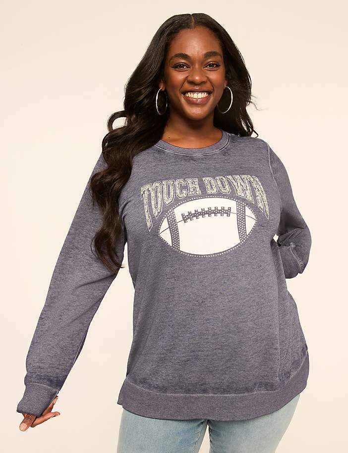 A smiling woman in a blue sweatshirt with a football graphic stands against a plain, light-colored background.