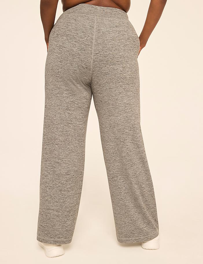 A person wearing gray sweatpants stands against a plain, light-colored background.