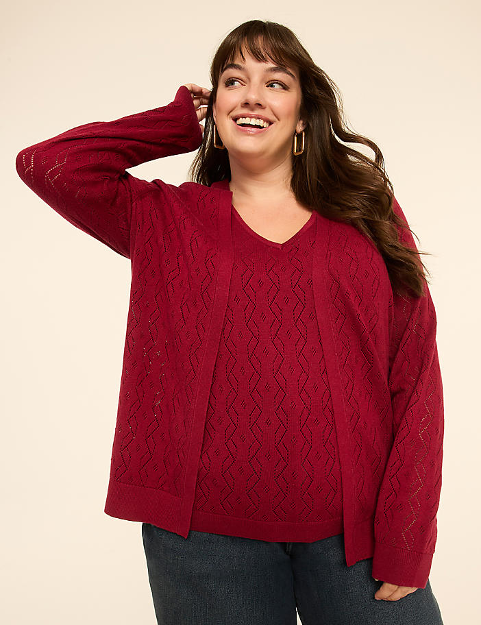 A smiling woman in a red knit sweater and blue jeans poses against a plain cream background.