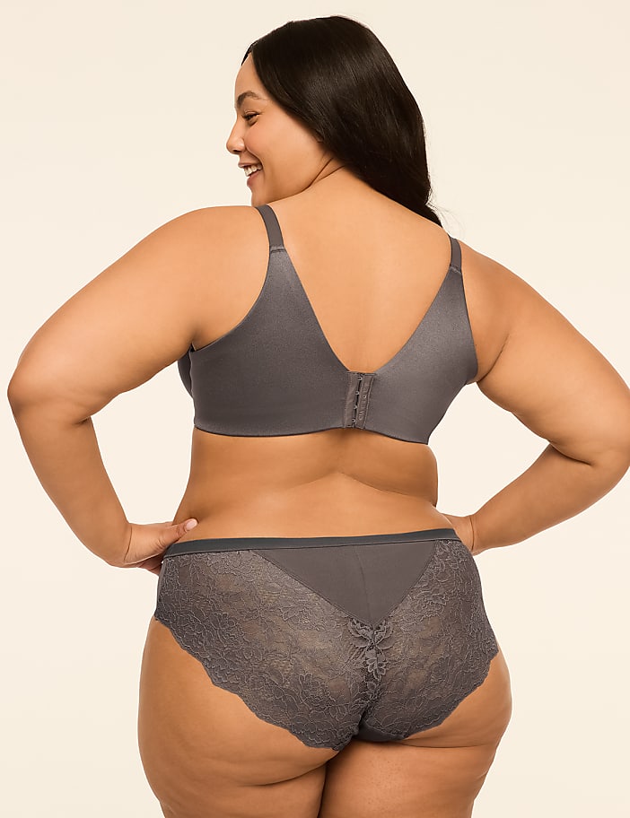 A woman in a grey bra and lace-trimmed underwear stands with her back to the viewer against a plain, light-colored background.