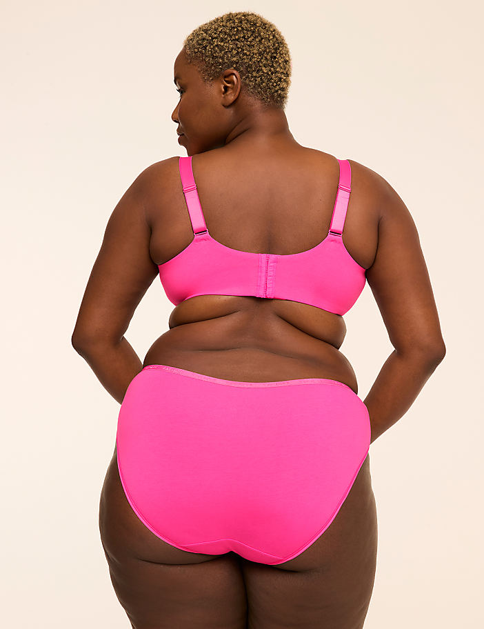 A woman in a bright pink bra and underwear stands with her back to the camera against a plain, light-colored background.