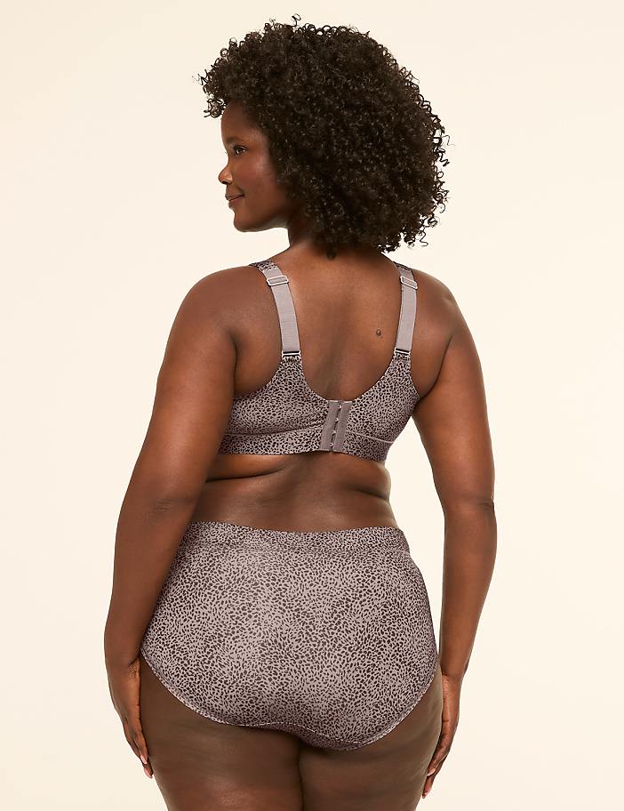 A woman in a patterned bra and underwear stands against a plain, light-colored background.
