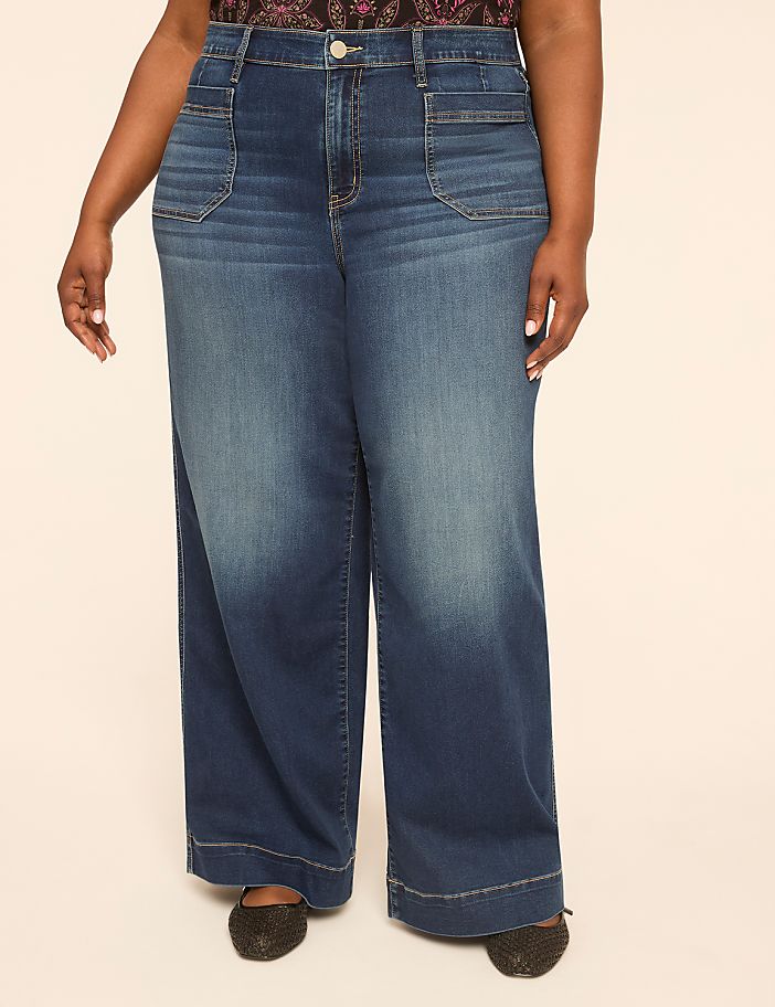 A person stands in the foreground wearing wide-leg denim jeans and sparkly shoes, against a plain, light-colored background.
