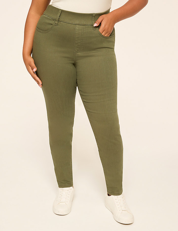 A person wearing olive green skinny jeans and white sneakers stands against a plain, light-colored background.