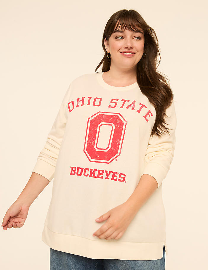 A smiling woman in a cream-colored Ohio State Buckeyes sweatshirt stands against a plain, light-colored background.