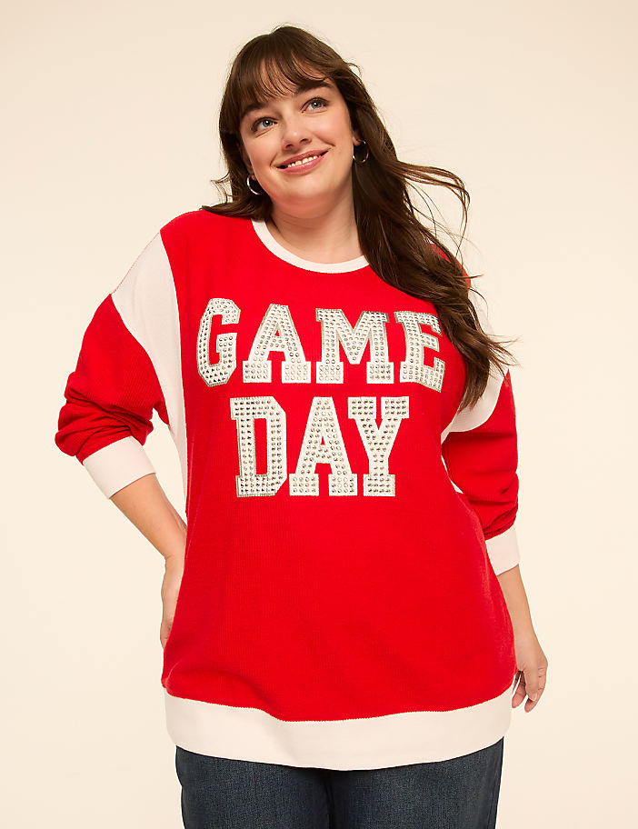 A smiling woman in a red "GAME DAY" sweatshirt stands against a plain, light-colored background.