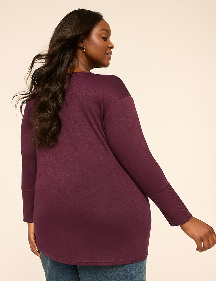 A woman in a burgundy sweater is shown from the back against a plain, light-colored background.