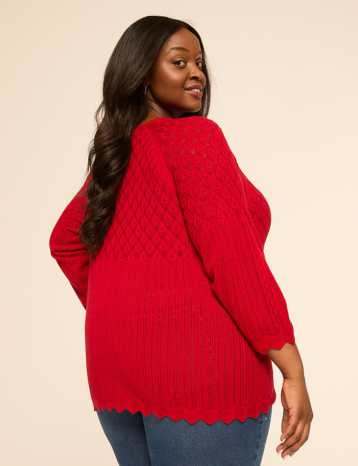 A woman in a red sweater and jeans poses against a plain, light-colored background.
