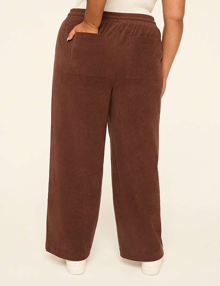 A person wearing brown corduroy pants stands against a plain, light-colored background.