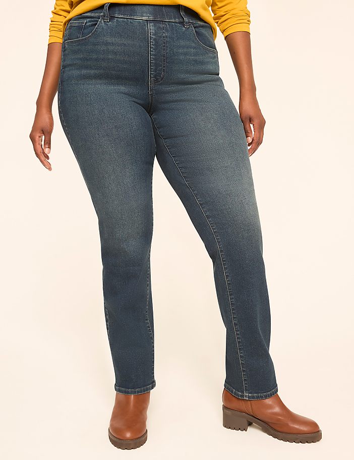 A person wearing blue jeans and brown boots stands against a plain, light-colored background.