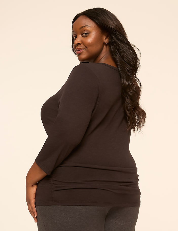 A woman with dark hair and a dark shirt is in the foreground, with a plain, light-colored background.