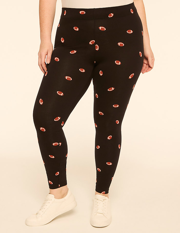 A person wearing black leggings with a football pattern stands against a plain, light-colored background.