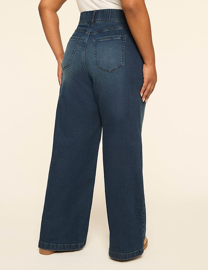 A person wearing wide-leg denim jeans stands against a plain, light-colored background.
