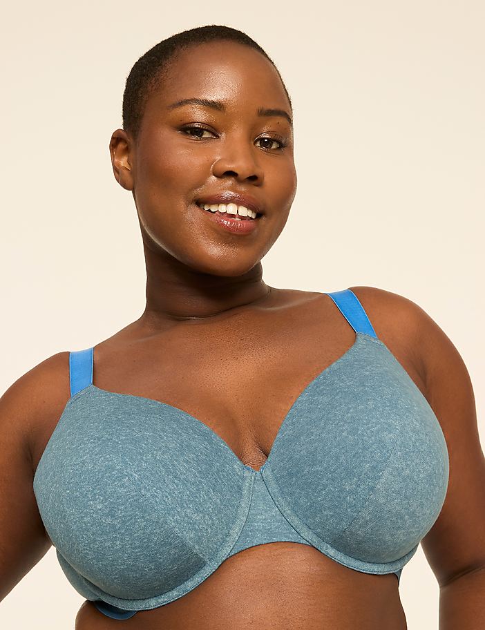 A smiling woman with short hair wears a blue bra in the foreground against a plain, light-colored background.