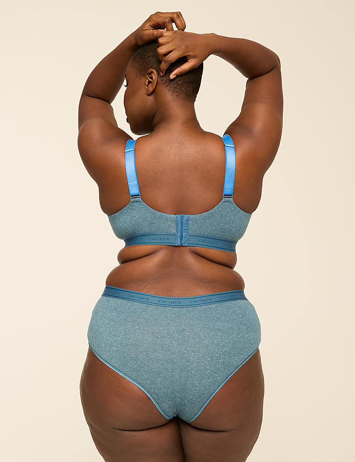 A woman in blue lingerie stands with her back to the viewer against a plain, light background.
