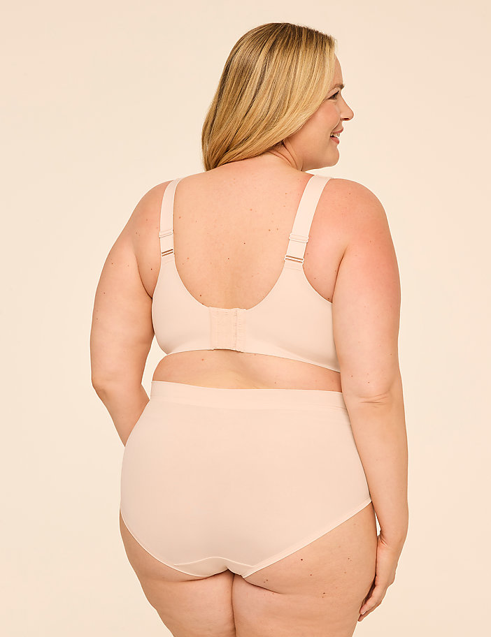 A woman in beige lingerie stands against a plain, light-colored background.