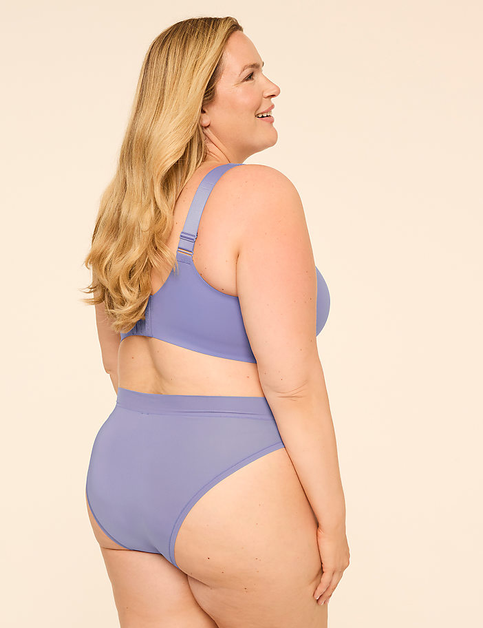 A woman in a lavender bra and underwear stands against a plain, light background.