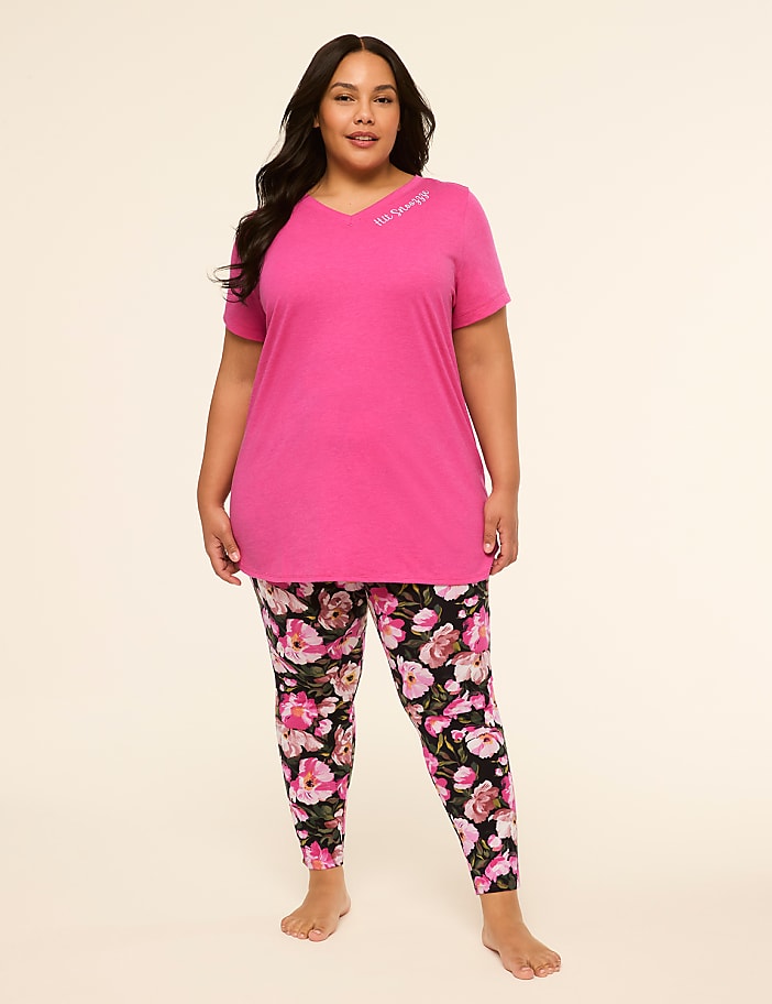 A woman in a pink tunic and floral leggings stands against a plain, light background.